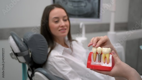 Dentist with a patient looking at a tomographic image of the teeth and discussing a treatment and implantation plan