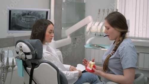 Dentist with a patient looking at a tomographic image of the teeth and discussing a treatment and implantation plan
