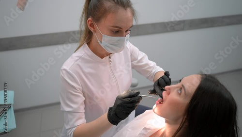 Female dentist examining a woman patient in modern dental office. Doctor at work in stomatology dentistry. Teeth research