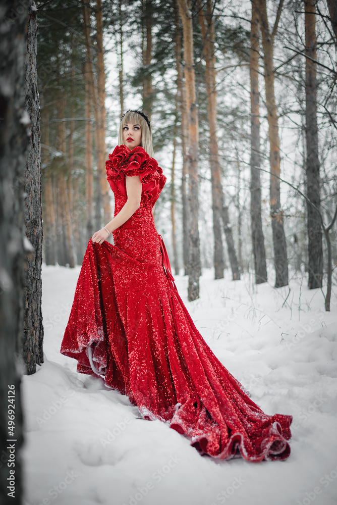 Young woman in the red dress walking by the winter forest. Young woman in the red dress walking by the winter forest.