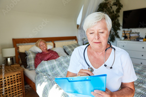 Ärztin schaut in Patientenakte bei Hausbesuch im Pflegeheim photo