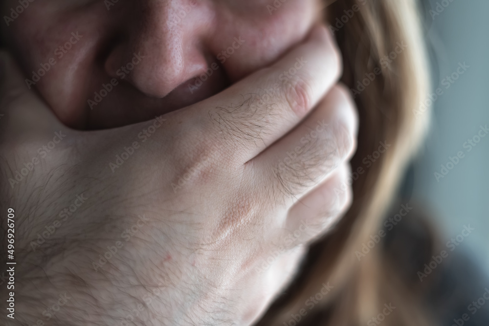 Close-up of a woman crying and a man's hand covering her mouth, a scene of gender violence.