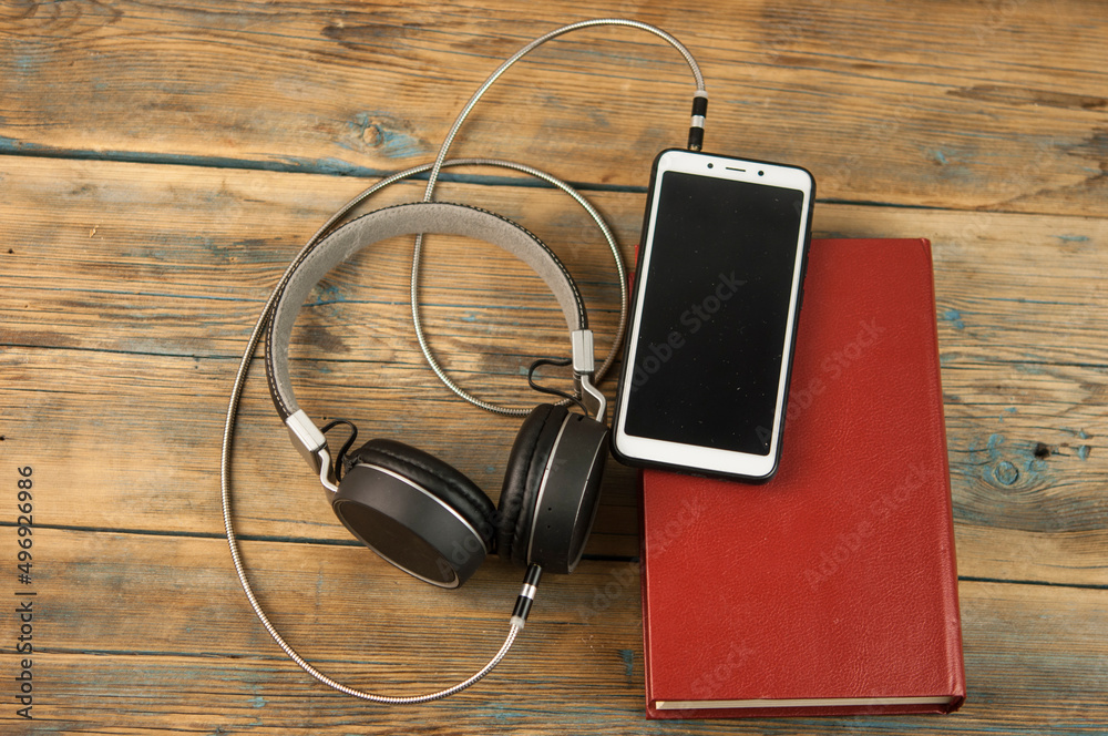 Audio book concept. Headphones and book over wooden table. Top view with space for your text