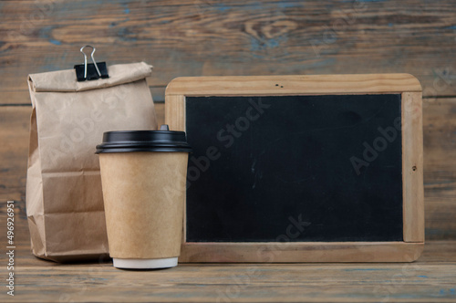 school lunch bag with blank blackboard on wood background