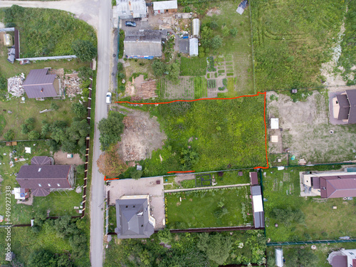 Top view at a plot of land marked with red, a village with rural houses and green land