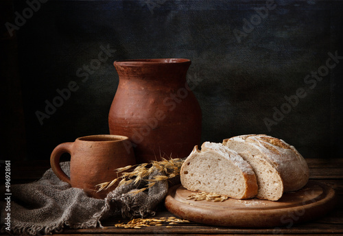 Homemade bread and vintage ceramic kitchenware on an old wooden table. Artistic Still Life in Vintage Style.