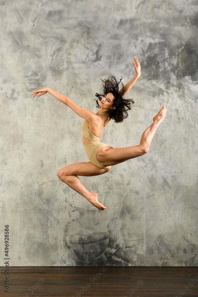 Flexible woman performing jump in studio