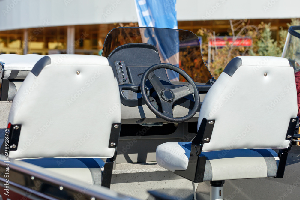 The steering wheel and white leather seats of a riverboat.