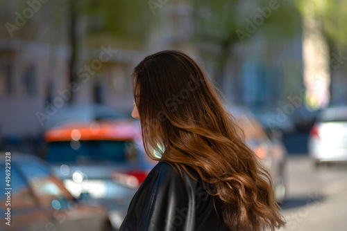 Young brunette woman standing on the side walk waiting to cross the street. Sunny day, spring, sunglasses, fresh, wavy hair