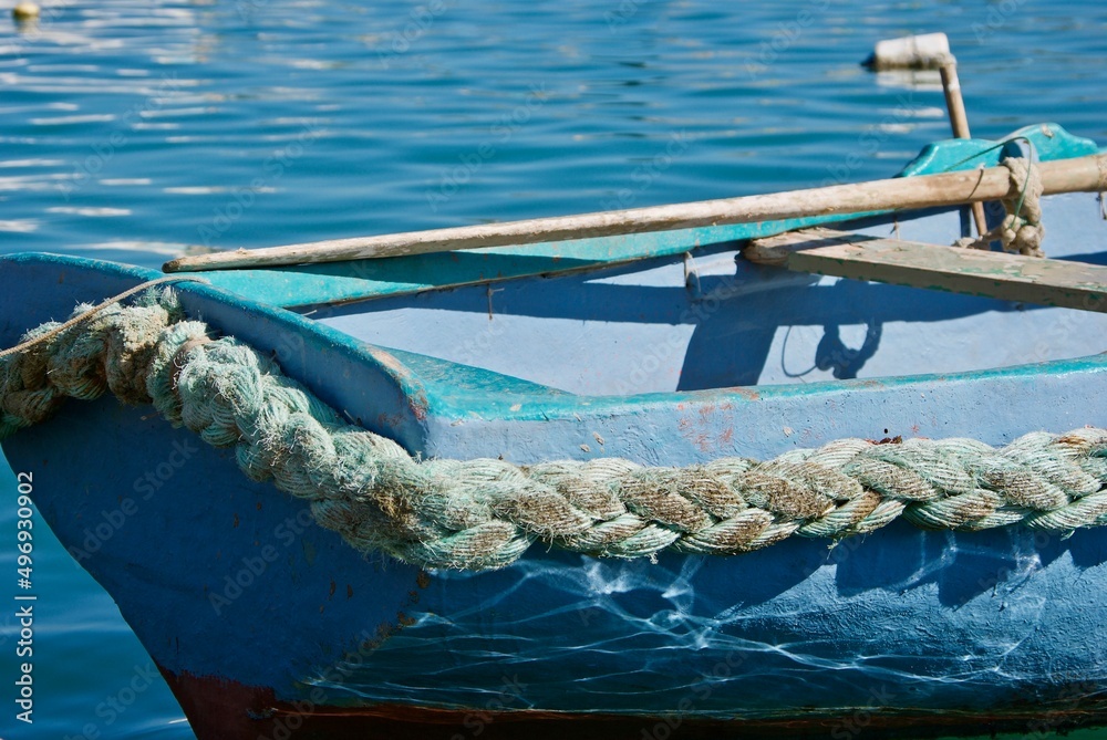 Obraz premium Detail of a small blue Maltese fishing boat with braided rope and oars.