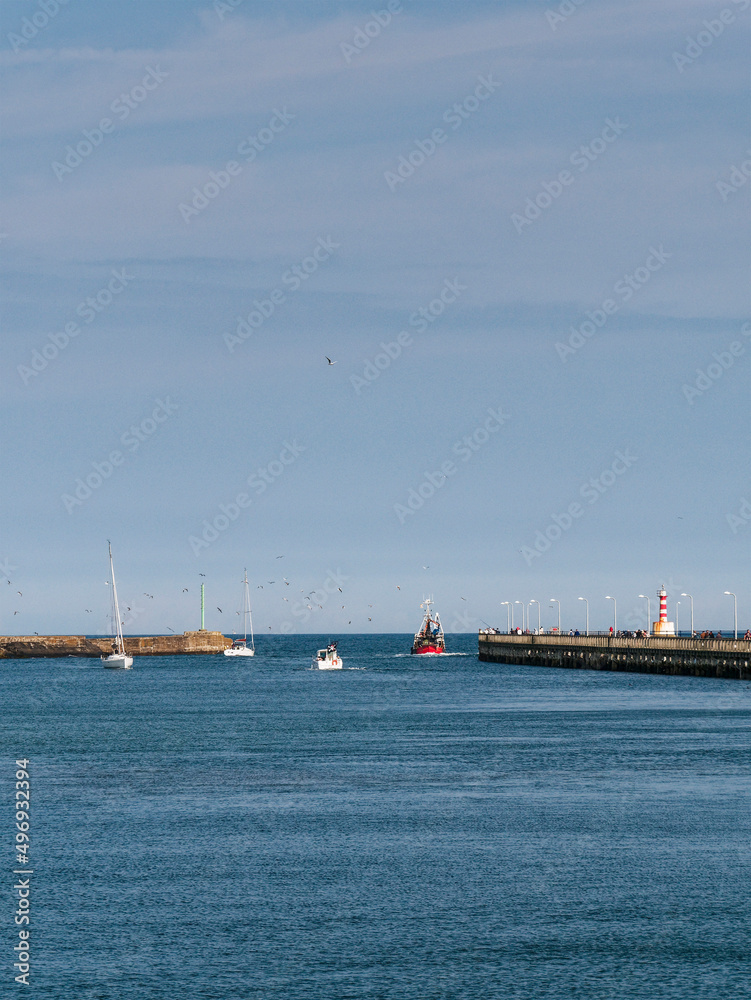 A fishing boat leaves Amble harbour in Northumberland, UK with copy space