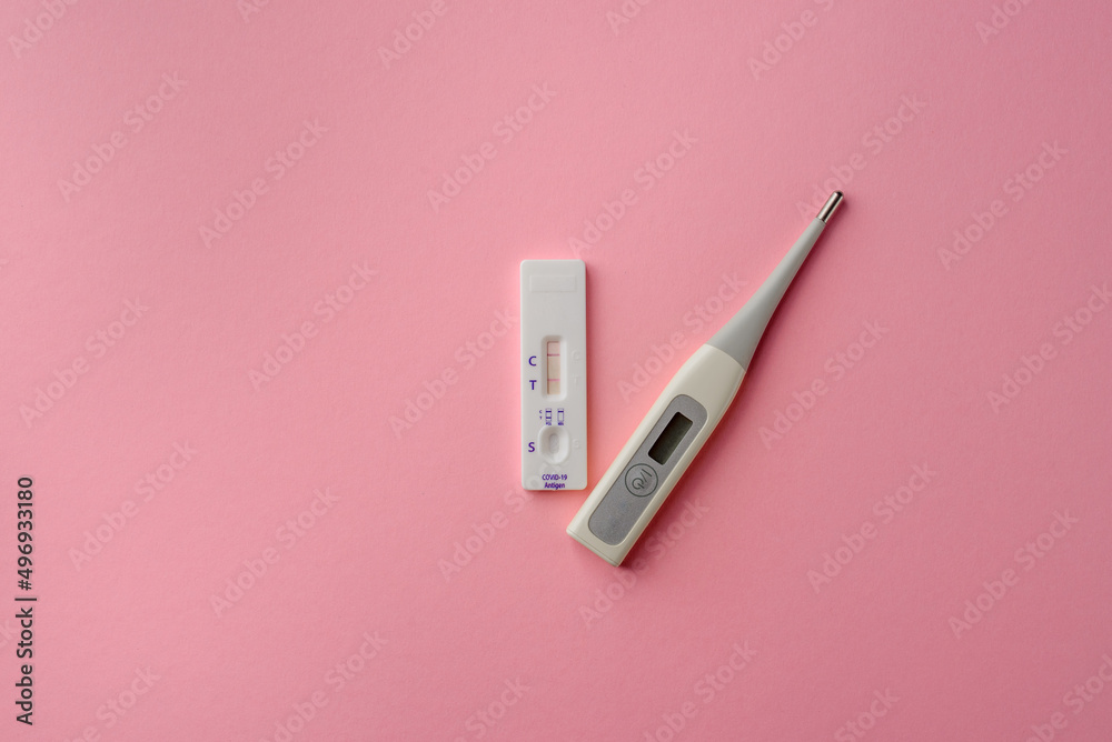Express test for covid-19 with a positive result and a thermometer on a pink background. Coronavirus self-test kit Express test for covid-19 with a positive result and a thermometer on a pink background. Coronavirus self-test kit