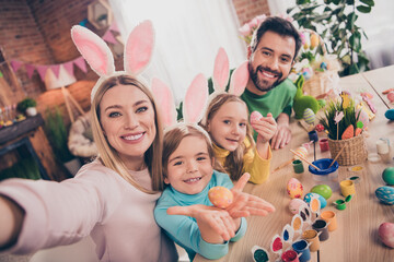 Photo of beautiful idyllic family four people take selfie showing painted eggs wear bunny ears home indoors