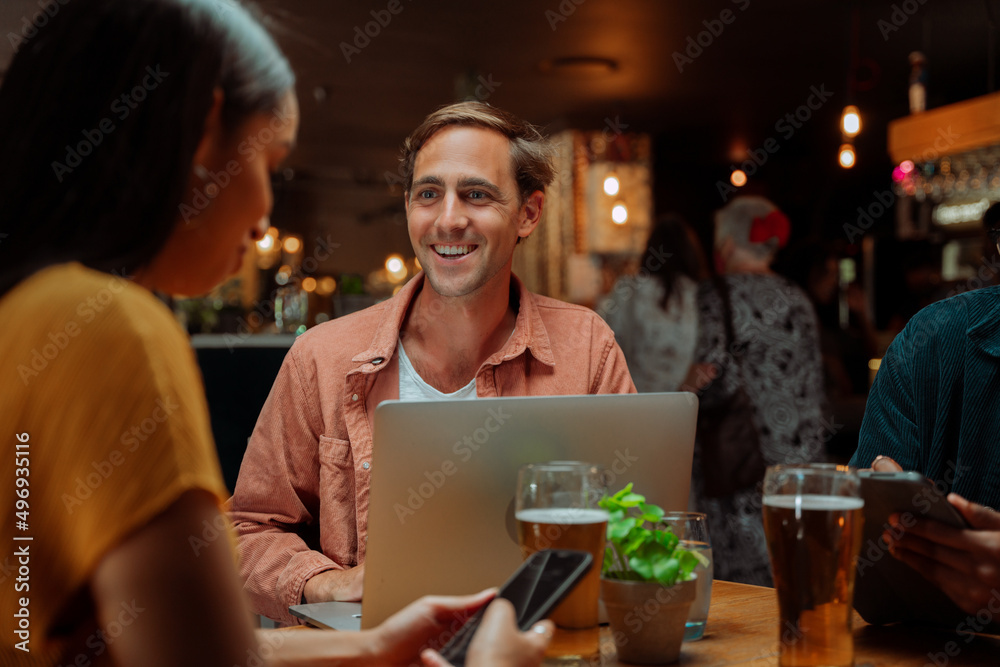 diverse colleagues out for drinks working at restaurant using laptop
