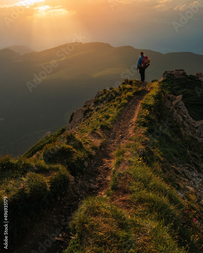 Backpacker, traveler standing on the dolomite mountain during sunset in Alps, Italy.