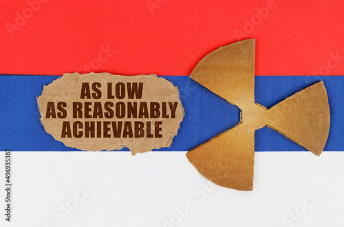 On the flag of Russia, the symbol of radioactivity and torn cardboard with the inscription As Low As Reasonably Achiev