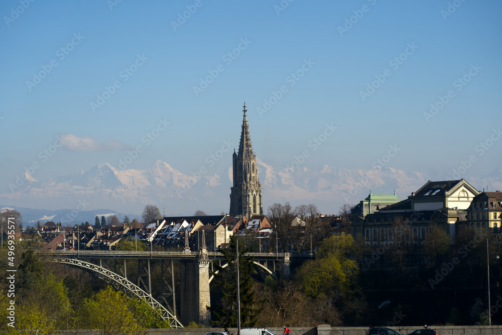 Fototapeta premium View over the old town of Bern with church Berner Minster and Swiss Alps in the background on a sunny spring afternoon. Photo taken April 4th, 2022, Bern, Switzerland.