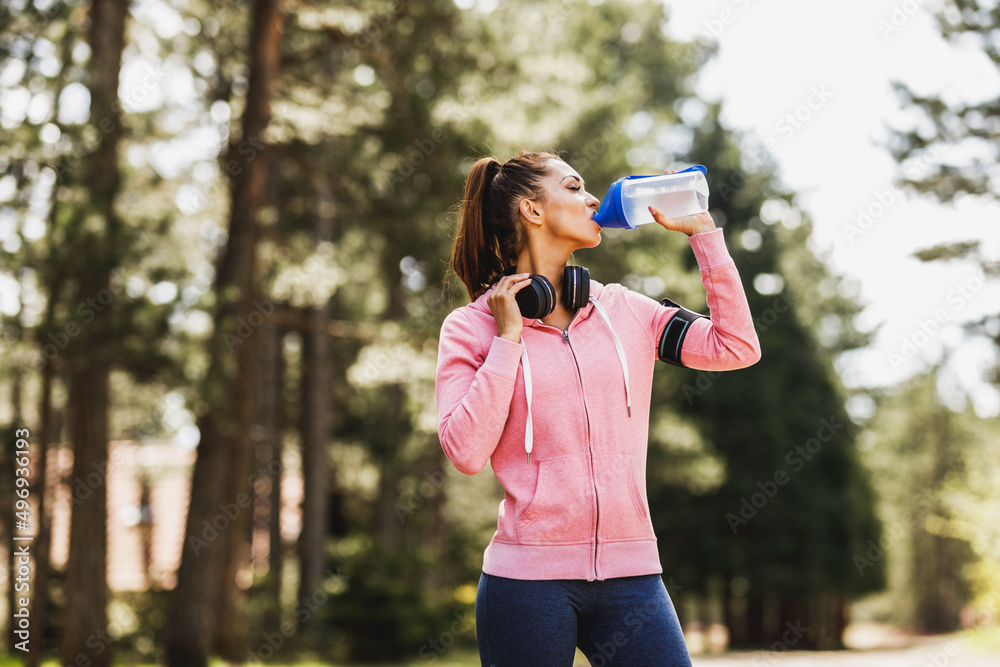 Woman Runner Is Drinking Water And Taking A Break After Jogging Outdoors Woman Runner Is Drinking Water And Taking A Break After Jogging Outdoors