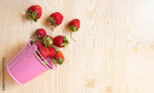 Composition of strawberries in a bucket on a table made of wooden boards, natural vitamin dessert