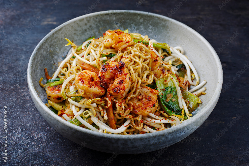 Modern style traditional stir-fried Thai phak kung with king prawns, vegetable and noodles served as close-up in a Nordic design bowl