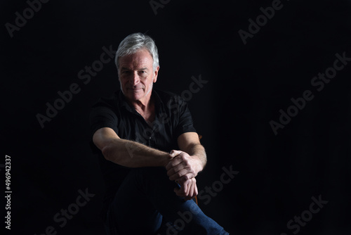 Foto front  view portrait of senior man sitting on chair on black background