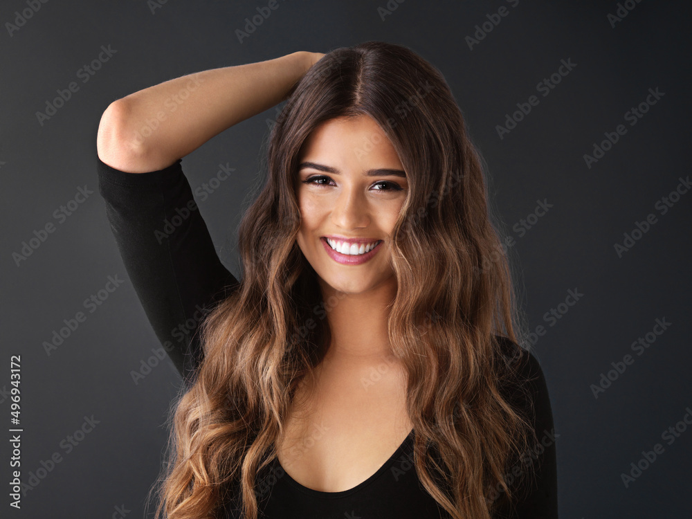 She knows every beauty trick in the book. Studio shot of a beautiful young woman against a dark background. She knows every beauty trick in the book. Studio shot of a beautiful young woman against a dark background.