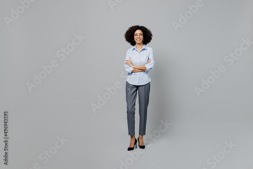 Full body smiling young employee business corporate lawyer woman of African American ethnicity in classic formal shirt work in office look camera hold hands crossed folded isolated on grey background. photo