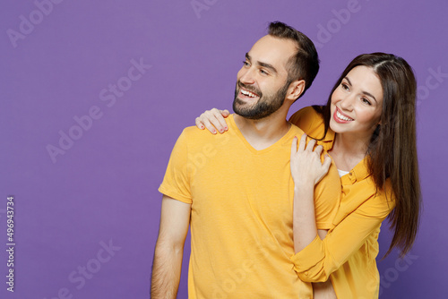 Young smiling fun happy lovely couple two friends family man woman 20s together wear yellow casual clothes looking aside on workspace area mcok up isolated on plain violet background studio portrait.