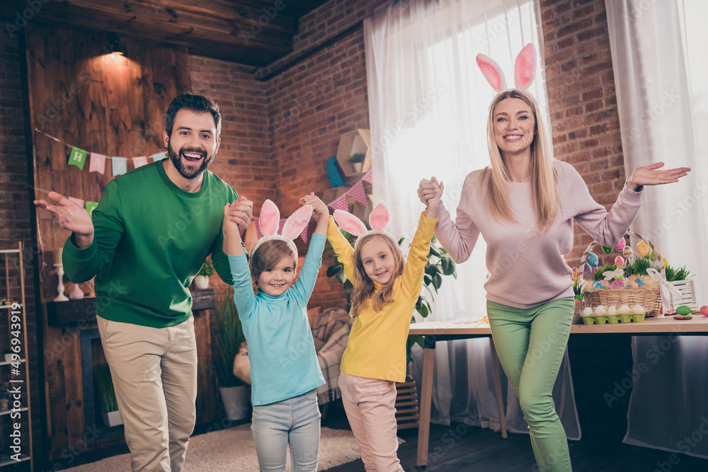 Fototapeta premium Portrait of four excited overjoyed people have fun hold arms wear bunny rabbit ears house indoors