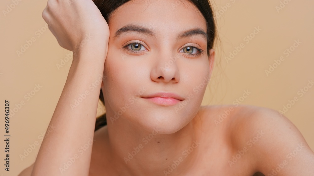 Close-up beauty portrait of young woman looks at camera props her head up with her hand | Skincare products promotional concept Close-up beauty portrait of young woman looks at camera props her head up with her hand | Skincare products promotional concept