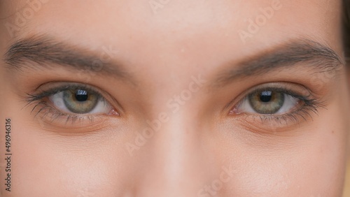 Obraz na plátne Extreme close-up of young woman opens her eyes and looks at camera, blinks and s
