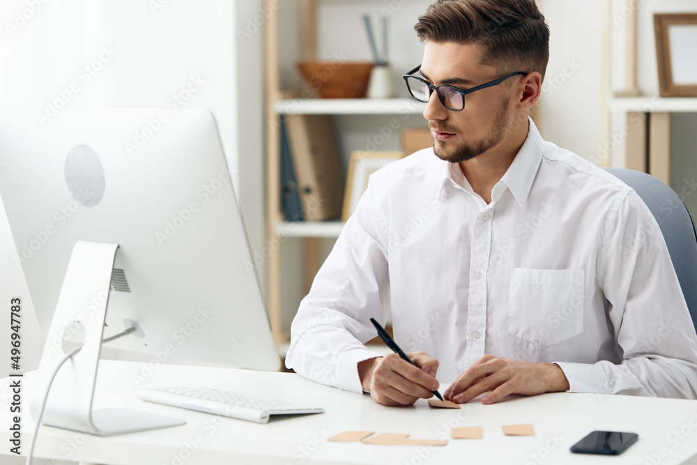 Fototapeta premium handsome businessman wearing glasses sits at a desk office worked technologies