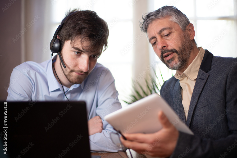 manager, chef d'équipe ou directeur qui travaille à côté d'un jeune employé ou stagiaire et qui supervise son travaille en lui donnant des conseils manager, chef d'équipe ou directeur qui travaille à côté d'un jeune employé ou stagiaire et qui supervise son travaille en lui donnant des conseils