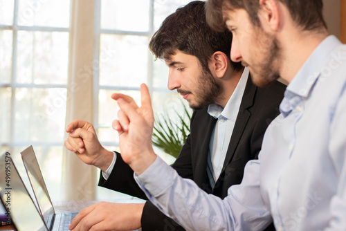 deux jeunes collègues, employés de bureau ou hommes d'affaires travaillent ensemble en collaboration devant un ordinateur portable