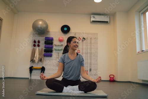 Young attractive woman meditating while practicing yoga in a gym