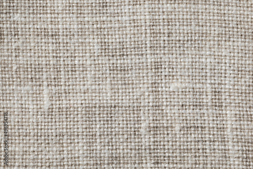 Texture of gray linen fabric close-up. Interlacing threads of uneven thickness.