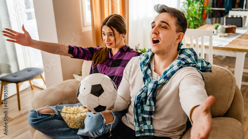 two people couple man and woman boyfriend and girlfriend or husband and wife sitting on the sofa at home watching football soccer game cheering copy space nervous anticipation and suspense photo