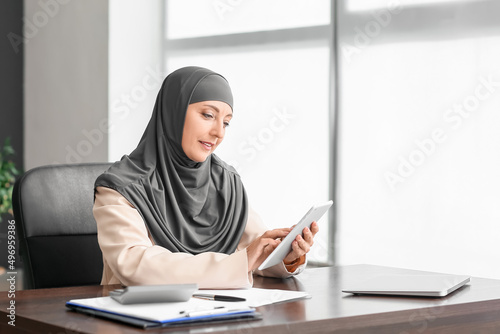 Muslim secretary with tablet working in office