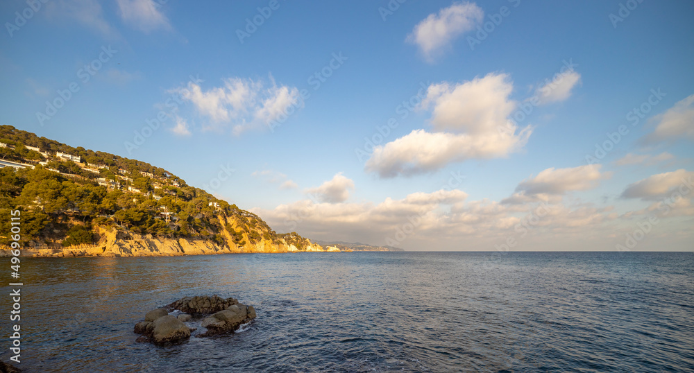 Naklejka premium Evening seascape with coastline illuminated by sunlight. View of the sea and part of the land.