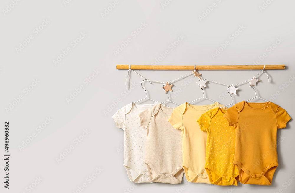 Baby bodysuits hanging on light wall