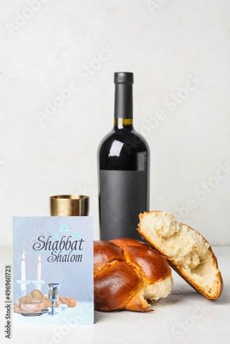 Traditional challah bread with greeting card and wine on white background. Shabbat Shalom photo