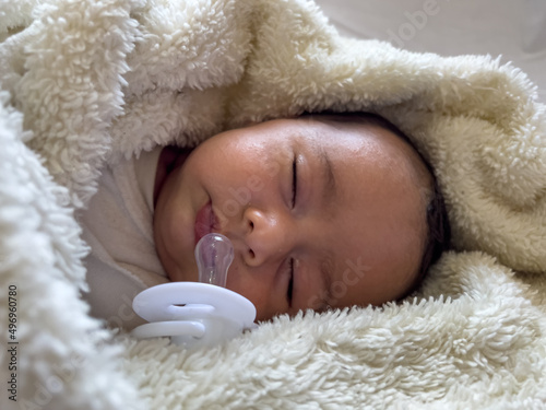 Sweet peaceful baby lying on a white bedsheet enjoy daytime nap photo