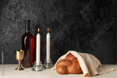 Traditional challah bread with wine and glowing candles on dark background. Shabbat Shalom photo