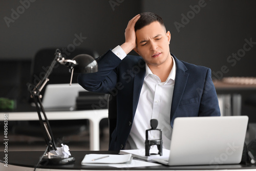 Worried young businessman sitting at table in office