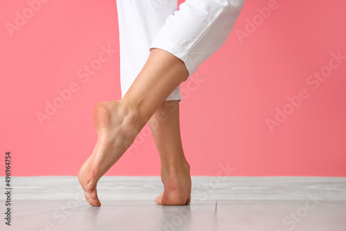 Female bare feet near pink wall, back view