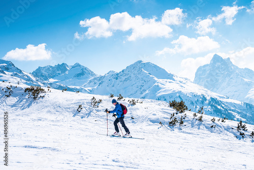 Male skier skiing on snow covered landscape. Scenic mountain range against sky. Tourist enjoying adventure sport during winter.
