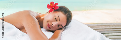 Massage spa and Body care outside on beach at luxury vacation resort. Asian beauty woman relaxing sleeping lying on table during aromatherapy treatment with coconut oil