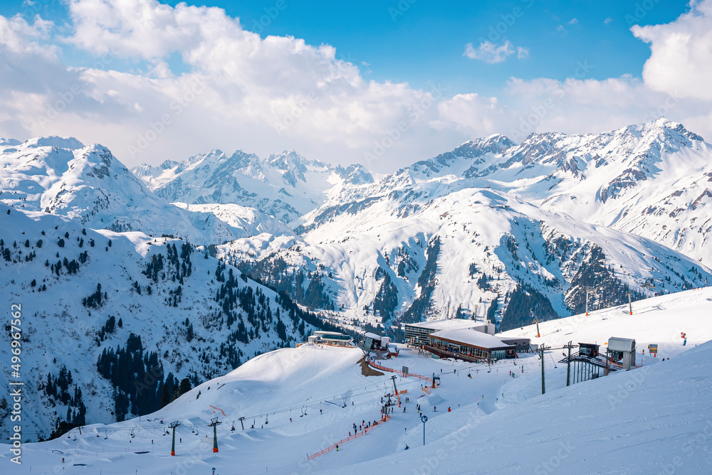 High angle view of resort in snow covered mountain. Winter sport on white landscape against sky. Idyllic scene during winter in alps.