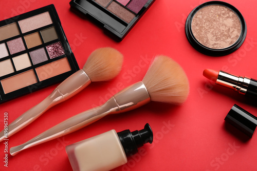 Composition with cosmetic products and makeup brushes on red background