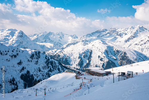 High angle view of resort in snow covered mountain. Winter sport on white landscape against sky. Idyllic scene during winter in alps.